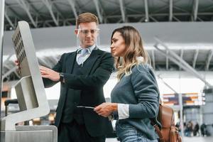 employé aidant à utiliser le terminal. jeune femme touriste est à l'aéroport pendant la journée photo