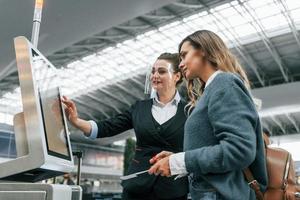 en utilisant la borne. jeune femme touriste est à l'aéroport pendant la journée photo