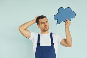 en uniforme bleu. homme debout dans le studio avec des signes vides pour le texte photo