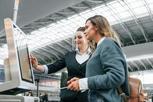 en utilisant la borne. jeune femme touriste est à l'aéroport pendant la journée photo