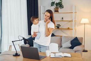 l'ordinateur portable est sur la table. mère avec sa petite fille est à la maison ensemble photo