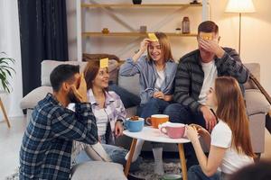 jouer qui suis-je jeu. un groupe d'amis fait la fête ensemble à l'intérieur photo