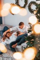 allongé sur le lit. famille heureuse célébrant les vacances à l'intérieur ensemble photo