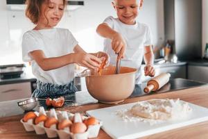 travailler avec de la pâte. petit garçon et fille préparant des biscuits de noël dans la cuisine photo