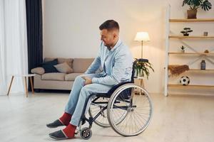 essayant de bouger. l'homme handicapé en fauteuil roulant est à la maison photo