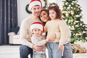 dans des chapeaux de Noël. famille célébrant le nouvel an avec leurs enfants à la maison photo