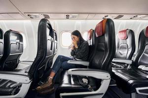 se sentir malade. une jeune femme en vêtements décontractés est assise sur le siège passager de l'avion photo