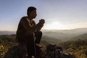 silhouette. homme priant Dieu sur la montagne. priez avec les mains avec foi en la religion et croyance en dieu sur la base de la bénédiction. le pouvoir de l'espoir ou de l'amour et de la dévotion. photo