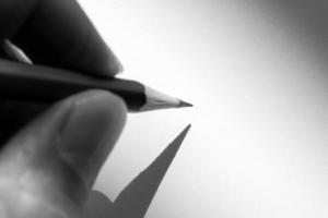 main humaine tenant un crayon pour écrire sur le papier dans l'ombre photo