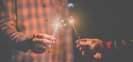 feux d'artifice brûlant un cierge magique dans des mains humaines dans la nuit de fête du nouvel an photo