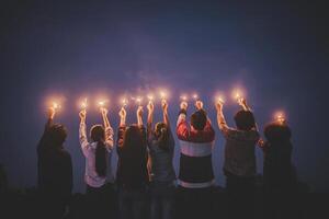 un groupe de jeunes amis s'amuse avec un cierge magique brûlant dans les mains ensemble photo