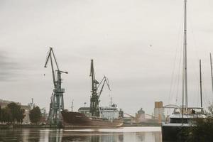 quais sur la martwa wisla en pologne ville de gdansk avec un cargo amarré en réparation et des grues portuaires en arrière-plan pendant le matin d'automne nuageux photo