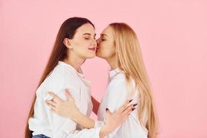 sur fond rose. jeune mère avec sa fille debout dans le studio photo