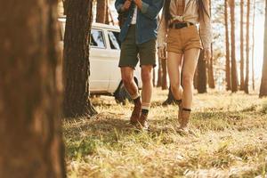 marcher sur l'herbe. jeune couple voyage ensemble dans la forêt pendant la journée photo