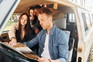 assis dans la voiture. un groupe de jeunes voyage ensemble dans la forêt pendant la journée photo