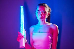 dans des verres. jeune femme à la mode debout dans le studio avec néon photo