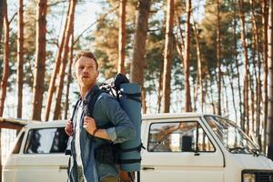 près de la voiture et du camp. l'homme voyage seul dans la forêt pendant la journée en été photo