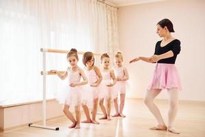 l'entraîneur enseigne aux enfants. petites ballerines se préparant à la performance en pratiquant des mouvements de danse photo