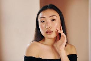 portrait de jeune femme asiatique sérieuse qui se tient à l'intérieur photo