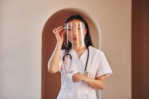 en tenue de protection. jeune femme asiatique sérieuse debout à l'intérieur photo