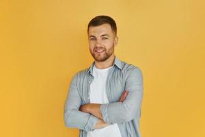 jeune homme en vêtements décontractés debout à l'intérieur dans le studio sur fond orange photo