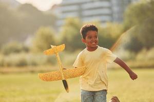 jouer avec l'avion. un enfant afro-américain s'amuse sur le terrain pendant la journée d'été photo