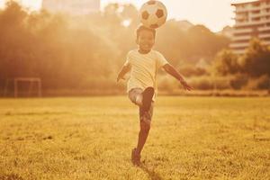 passer du temps actif le week-end. un enfant afro-américain s'amuse sur le terrain pendant la journée d'été photo