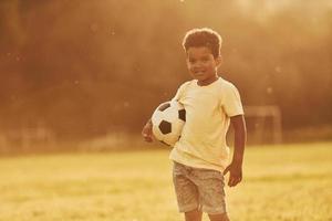 éclairé par la lumière du soleil. un enfant afro-américain s'amuse sur le terrain pendant la journée d'été photo