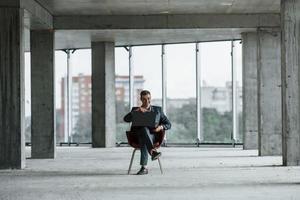 homme d'affaires à l'intérieur du bâtiment. un jeune homme en tenue de soirée travaille à l'intérieur sur la construction photo