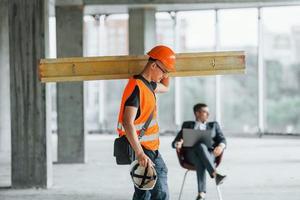 objet en mouvement. homme en costume et bricoleur en vêtements de protection orange travaille sur la construction photo