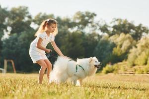 en promenade. petite fille avec son chien s'amuse sur le terrain pendant la journée ensoleillée photo