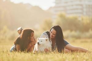 deux femmes avec un chien s'amusent sur le terrain pendant la journée ensoleillée photo