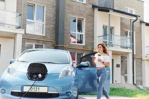 en utilisant le téléphone. jeune femme en vêtements décontractés avec son électromobile à l'extérieur pendant la journée photo