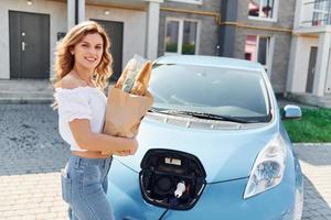 après les achats. jeune femme en vêtements décontractés avec son électromobile à l'extérieur pendant la journée photo