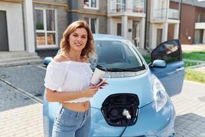 avec une tasse de boisson. jeune femme en vêtements décontractés avec son électromobile à l'extérieur pendant la journée photo