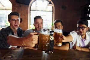 boire de la bière. gens en vêtements décontractés assis dans le pub photo