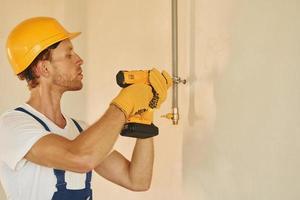 avec équipement. jeune homme travaillant en uniforme à la construction pendant la journée photo