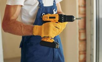 à l'aide d'outil. jeune homme travaillant en uniforme à la construction pendant la journée photo