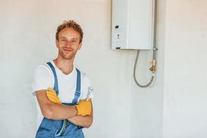 réparation de chauffe-eau. jeune homme travaillant en uniforme à la construction pendant la journée photo