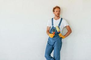 contre les murs blancs. jeune homme travaillant en uniforme à la construction pendant la journée photo