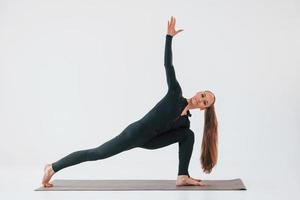 vue de côté. jeune femme en vêtements sportifs faisant de la gymnastique à l'intérieur photo