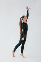 debout dans l'atelier. jeune femme en vêtements sportifs faisant de la gymnastique à l'intérieur photo