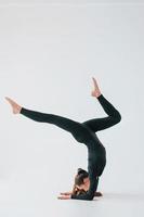 routine de pratique. jeune femme en vêtements sportifs faisant de la gymnastique à l'intérieur photo