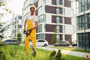 bâtiments modernes. l'homme a coupé l'herbe avec une tondeuse à gazon à l'extérieur dans la cour photo