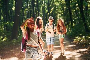 fille regardant au loin. enfants se promenant dans la forêt avec équipement de voyage photo