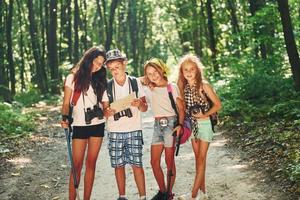 vue de face. enfants se promenant dans la forêt avec équipement de voyage photo