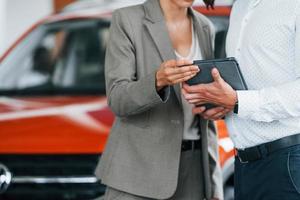 véhicules modernes. homme en tenue de soirée aidant le client à choisir l'automobile photo