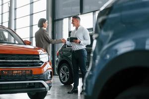 faire un accord. homme en tenue de soirée aidant le client à choisir l'automobile photo