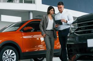 véhicules modernes. homme en tenue de soirée aidant le client à choisir l'automobile photo