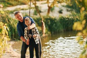 tenant la prise. père et fils sur la pêche ensemble à l'extérieur en été photo